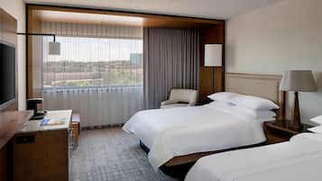 Una habitación de hotel con una cama grande, un escritorio, una silla y un televisor.