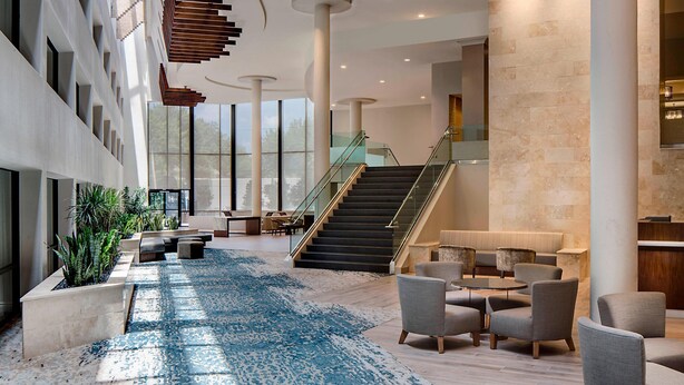 A spacious lobby with a central staircase, seating area, and large windows. - San Antonio Marriott Northwest Medical Center (San Antonio)