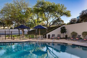 Una piscina al aire libre, sombrillas, sillones reclinables de piscina