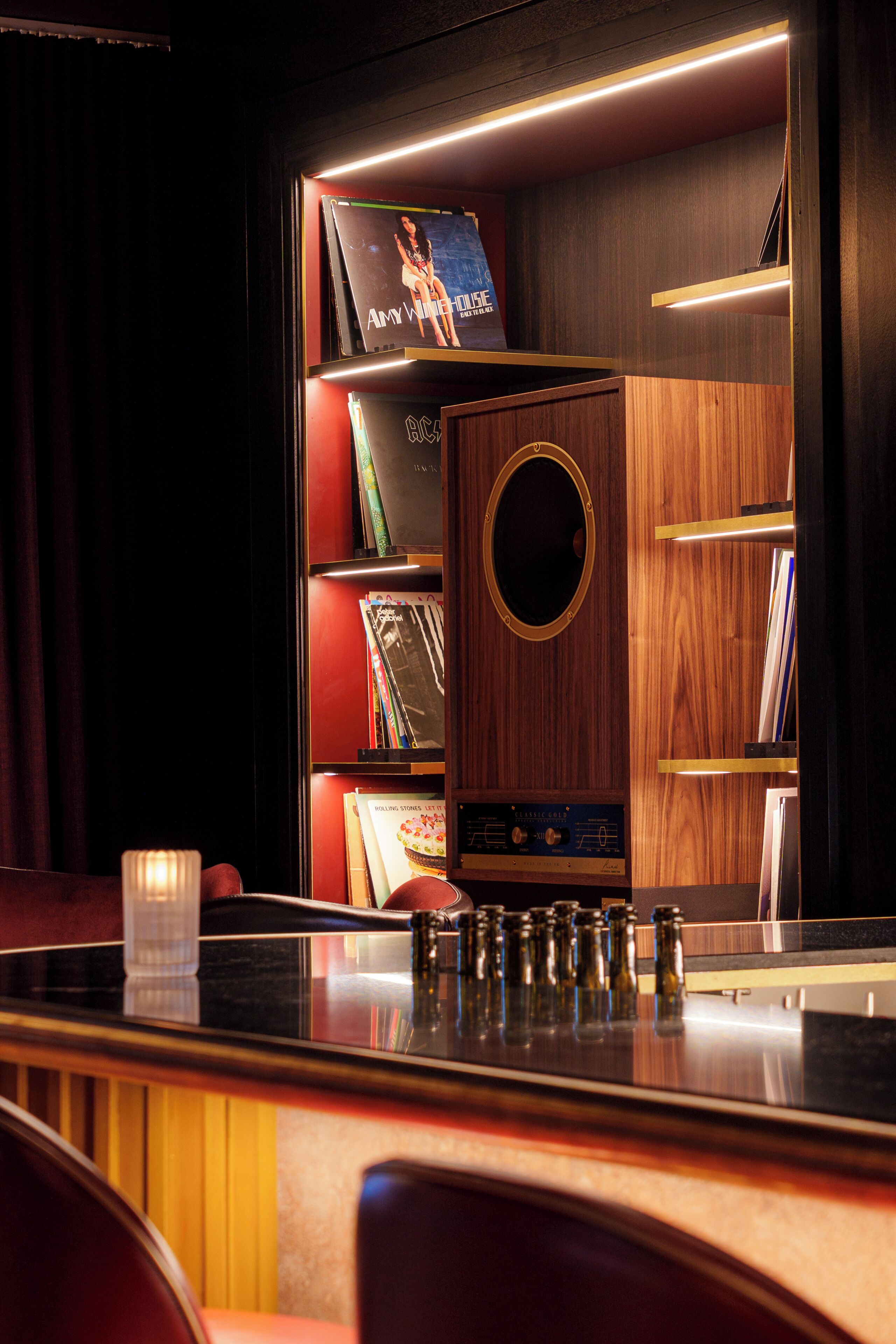 A bar area with a wooden bar counter, a radio, and bookshelves with various books and magazines.