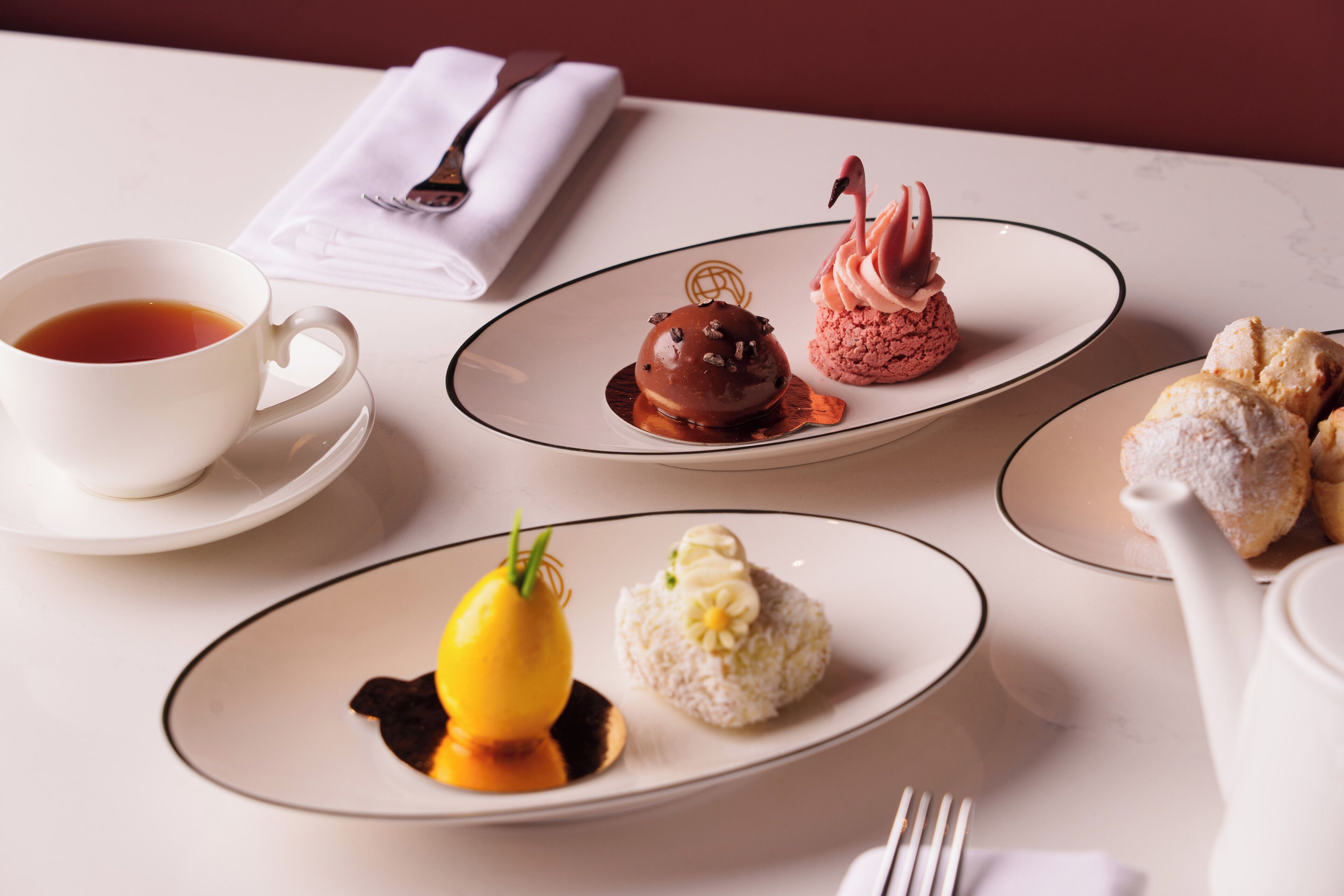 A table with a cup of tea, three dessert plates, and a teapot.