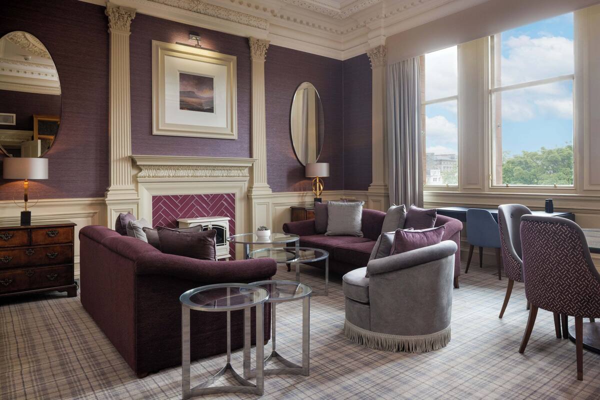 A spacious living room with a fireplace, comfortable seating, and large windows offering a view.
