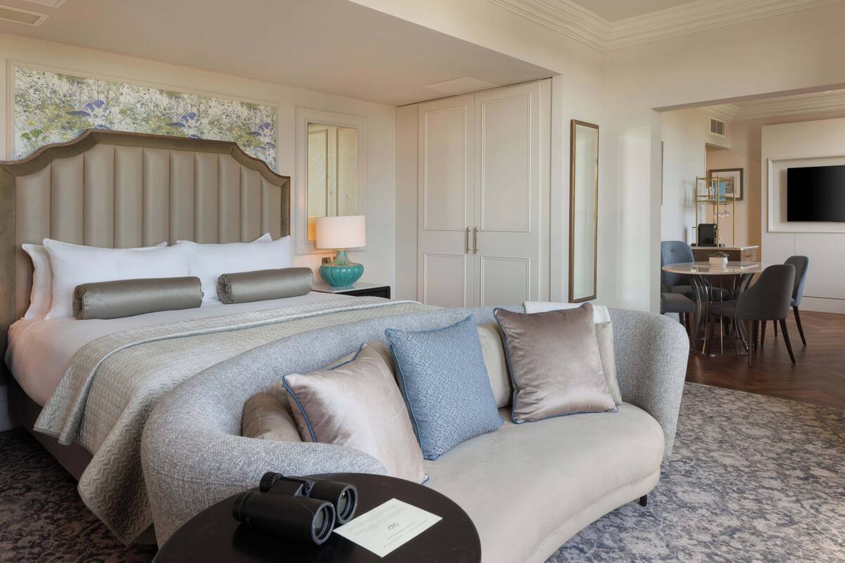 A hotel room with a large bed, a sofa, a desk, and a television.