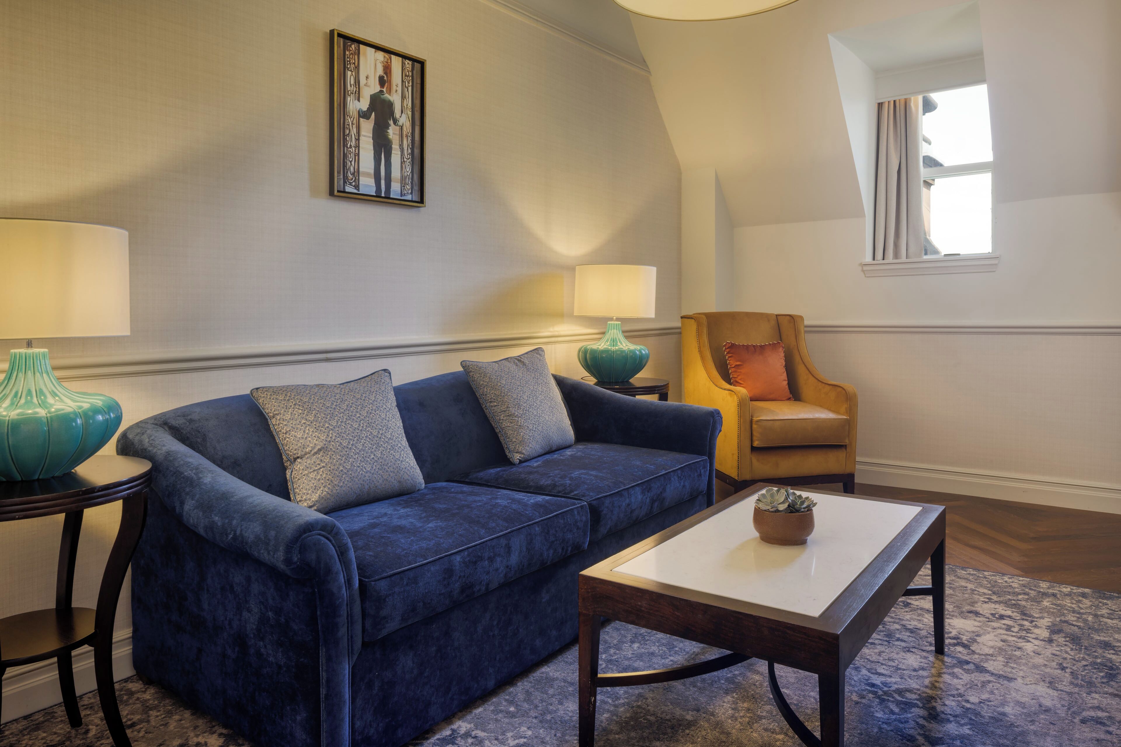 A living room with a blue sofa, a wooden coffee table, and two lamps.