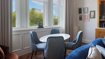 Una habitación con una mesa redonda, cuatro sillas, un sofá azul y una estantería.