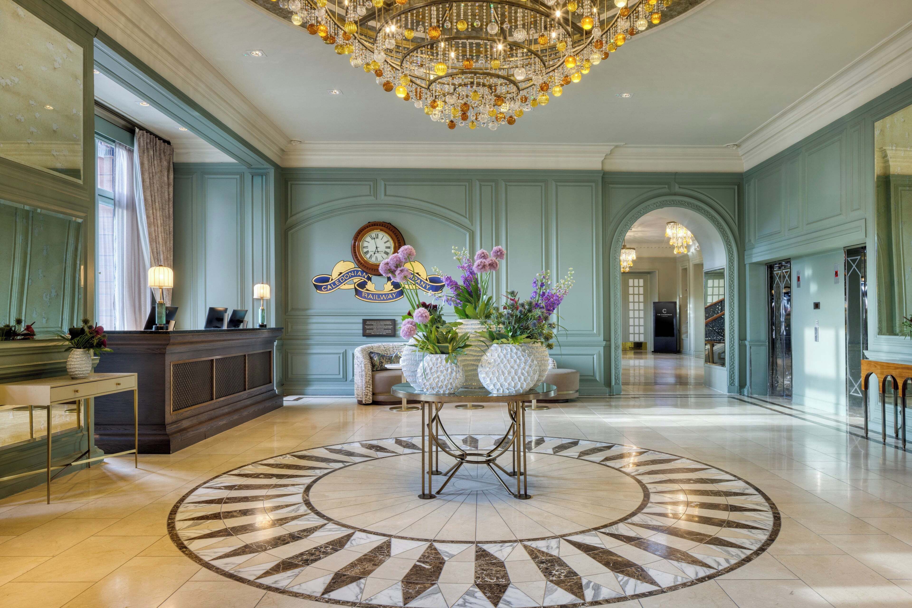 A spacious lobby with a grand chandelier, a reception desk, and a decorative clock. - The Caledonian Edinburgh, Curio Collection by Hilton (Edinburgh)