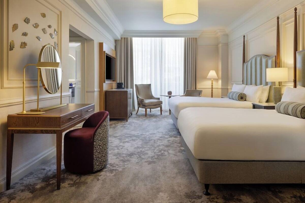 A hotel room with a bed, desk, chair, lamp, and a television.