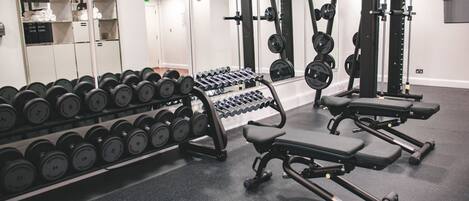 A gym with weightlifting equipment, dumbbells, and benches.