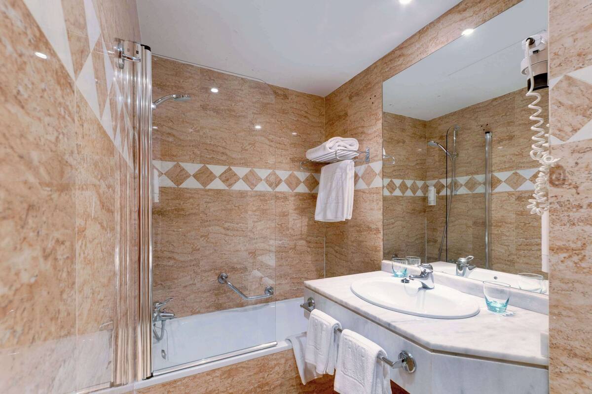 Ein modernes Badezimmer mit einer Glasdusche, einer Badewanne und einem Doppelwaschtisch.