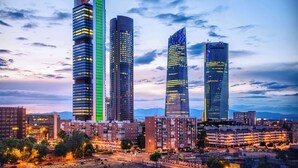 Une vue urbaine mettant en scène quatre gratte-ciel imposants, chacun se distinguant par son architecture originale et ses fenêtres illuminées.