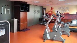 Une salle de sport équipée de vélos d’appartement, d’un téléviseur et d’une affiche motivante.