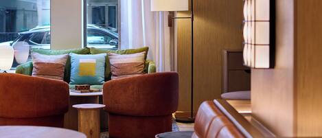 Un hall d’hôtel moderne avec des canapés en cuir, une table basse et un lampadaire.