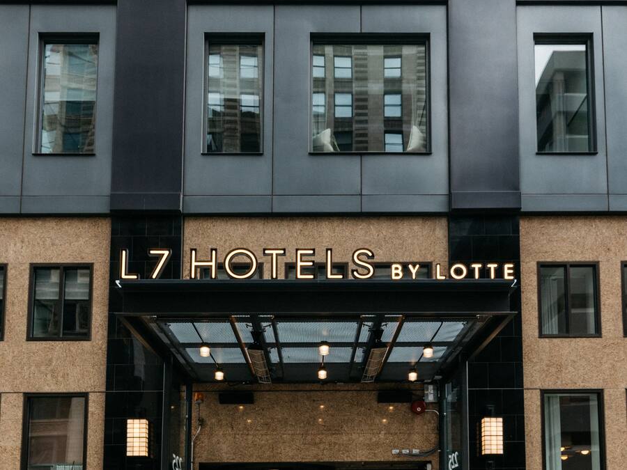 The entrance of L7 Hotels by Lotte, featuring a modern facade with large windows and a glass entrance.