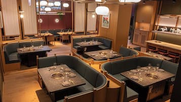 Un restaurante con cabinas y mesas, suelo de madera e iluminación colgante.