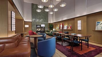 Um hall de hotel moderno com assentos de couro, lareira, obras de arte e um espaço para refeições.