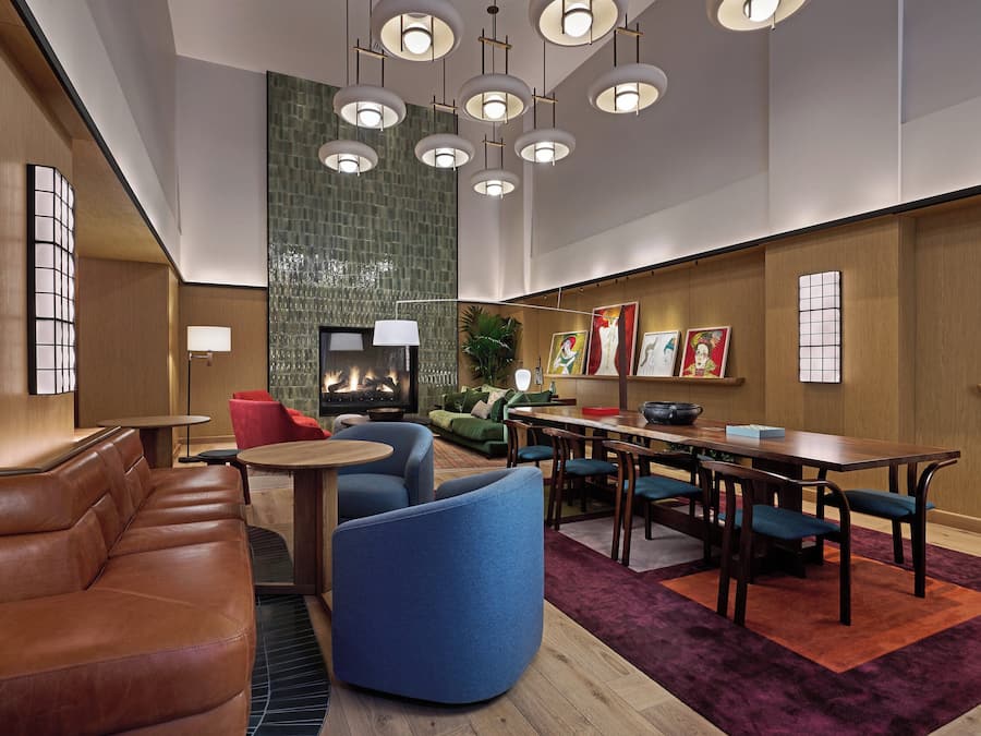 Um hall de hotel moderno com assentos de couro, lareira, obras de arte e um espaço para refeições.