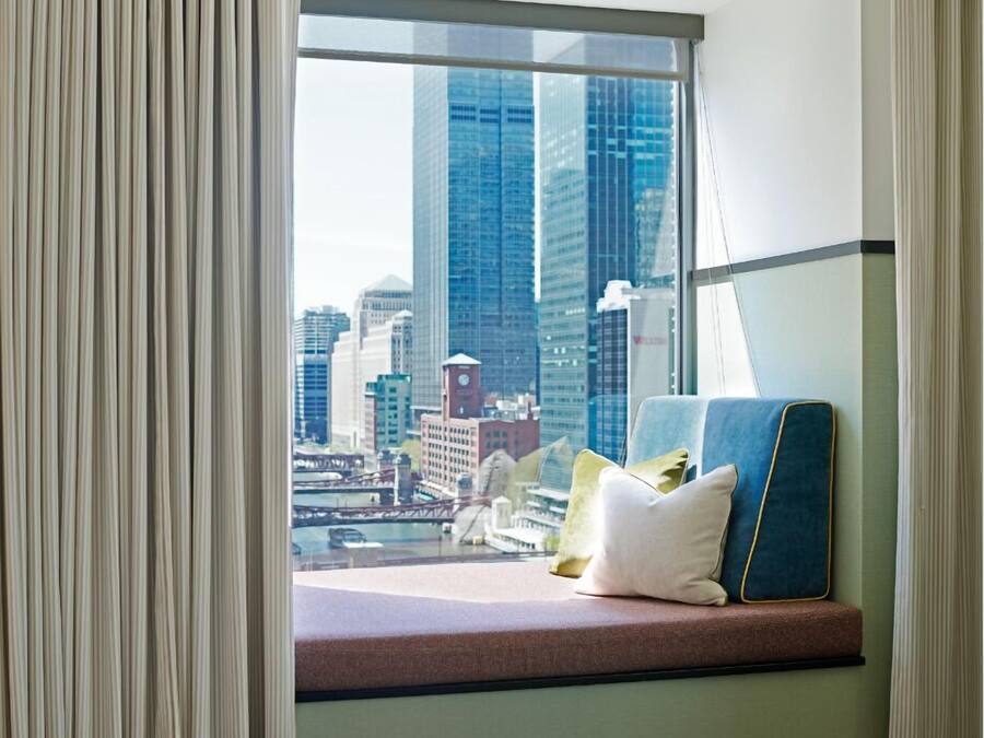 A city view from a window with a bench and pillows.