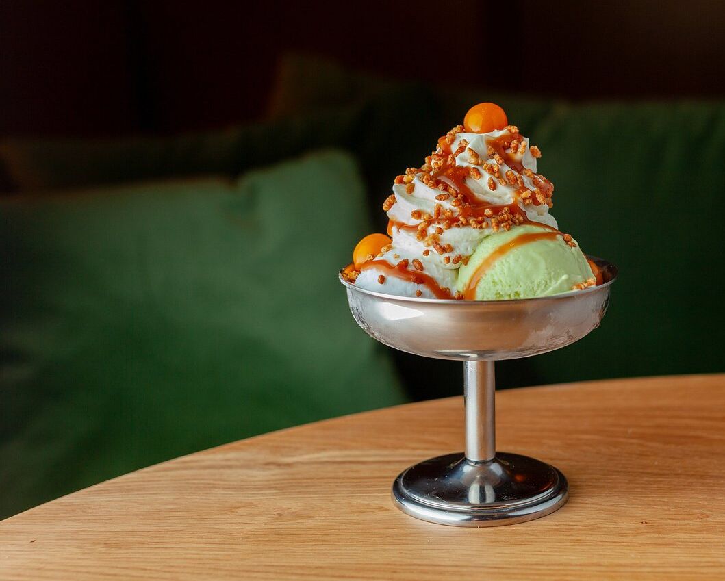 A dessert in a metal bowl on a wooden table.