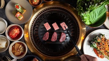 Uma churrasqueira com vários pedaços de carne, acompanhamentos e condimentos variados.