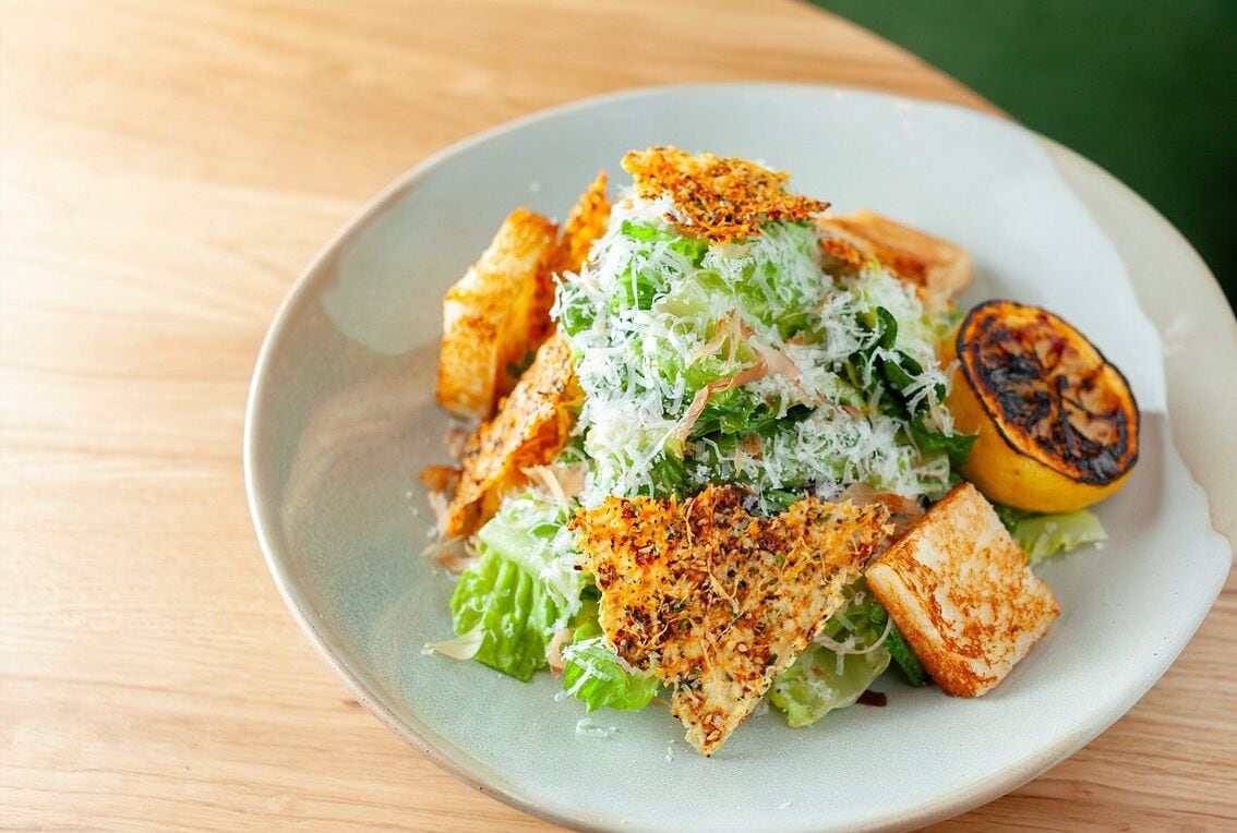 Un plato de comida con ensalada, plátano a la parrilla y croutons.