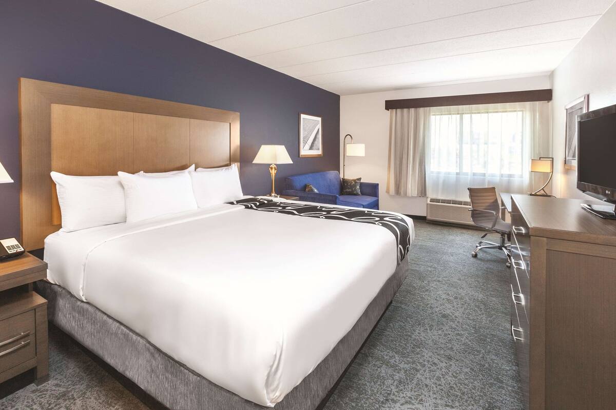 Une chambre d’hôtel avec un grand lit, un bureau, une chaise, une télévision et une vue sur l’extérieur.