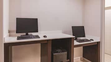 Un espacio de oficina moderno con dos escritorios, cada uno con monitor de computadora, teclado y ratón. Hay una impresora en el escritorio de la izquierda.