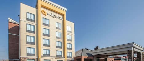 A multi-story hotel with a prominent 'Quinta' logo, a parking lot, and a gas station.