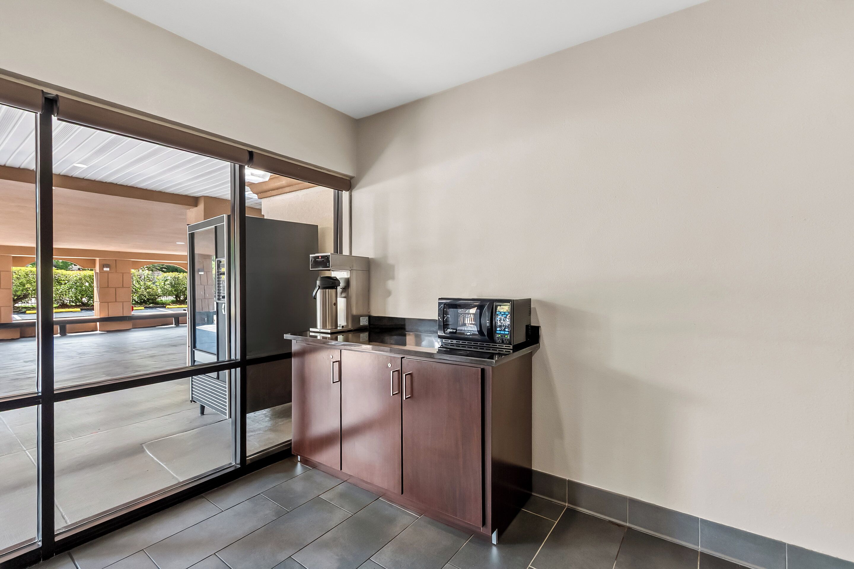 A modern kitchen with a built-in microwave, a refrigerator, and a coffee machine.