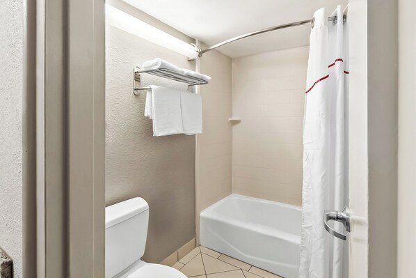 A bathroom with a toilet, a bathtub, and a shower curtain.