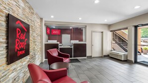 A Red Roof Inn reception area with a modern design, including a brick wall, red seating, and a staircase leading to an outdoor area. - Red Roof Inn Washington, DC (Washington)