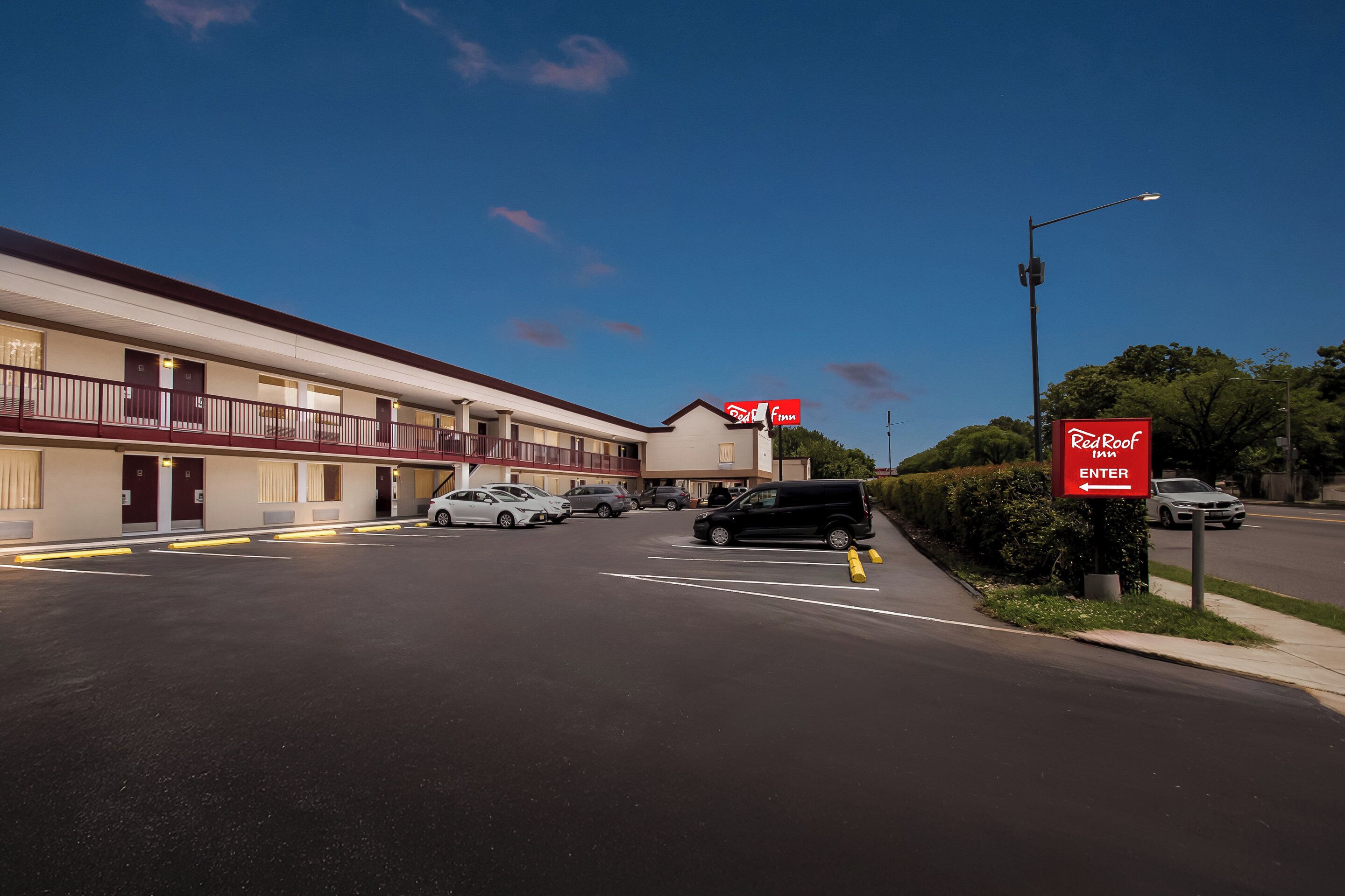 Um Red Roof Inn com um edifício de dois andares, estacionamento e vista para a rua.