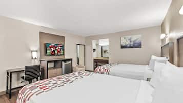 A hotel room with two beds, a desk, a chair, a television, and artwork on the walls.