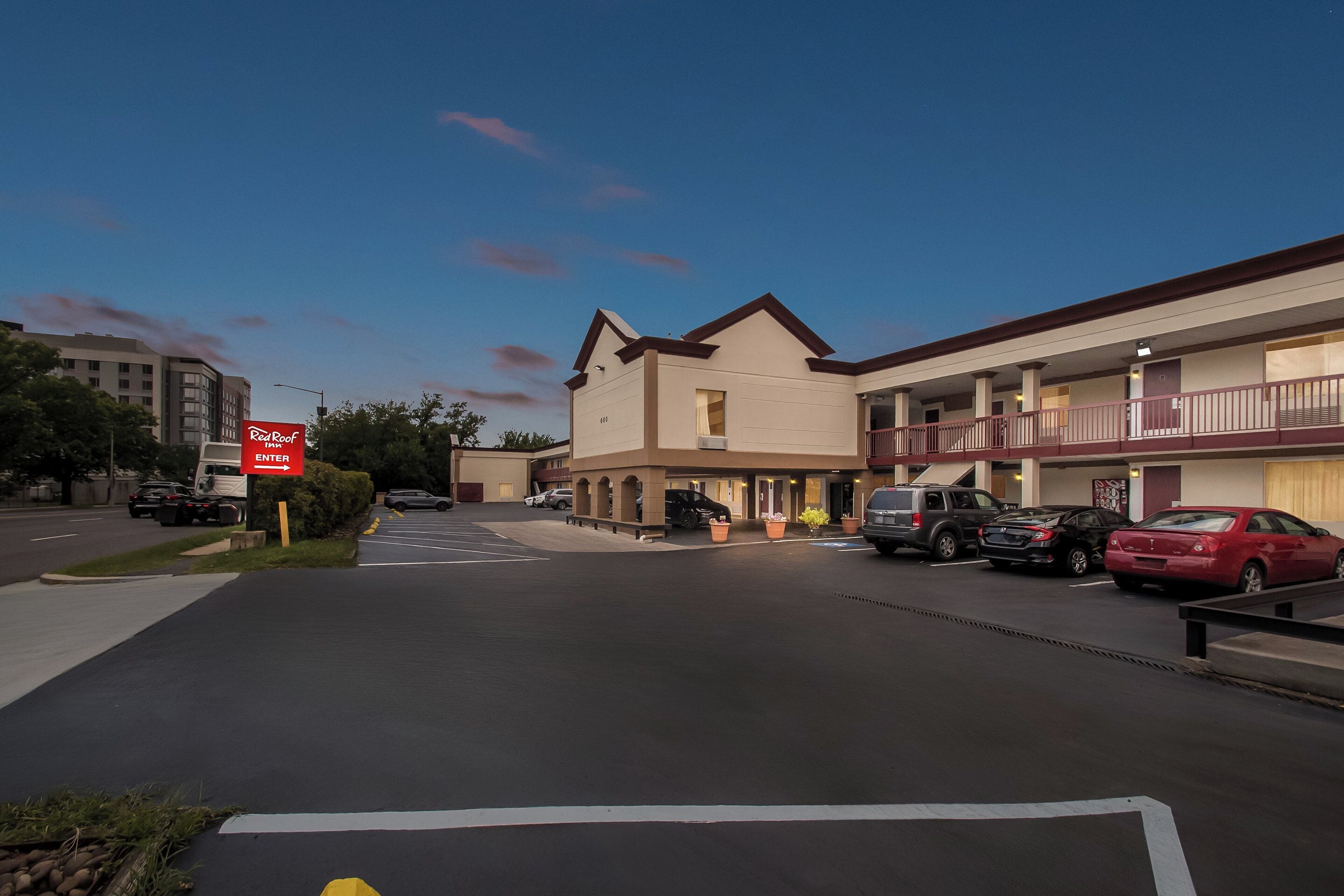 A hotel with a parking lot, a sign for 'ReRoof', and several parked cars.