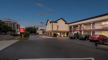 A hotel with a parking lot, a sign for 'ReRoof', and several parked cars.