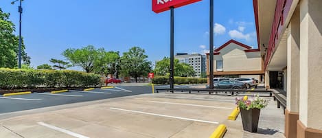 A Red Roof Inn sign, a parking lot, and a building with a beige facade.