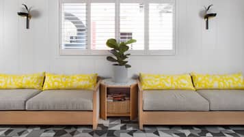 A modern living room with a sofa set, a potted plant, and a bookshelf.