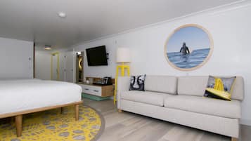 Ein modernes Hotelzimmer mit Bett, Sofa, Fernseher und einer runden Wanddekoration.