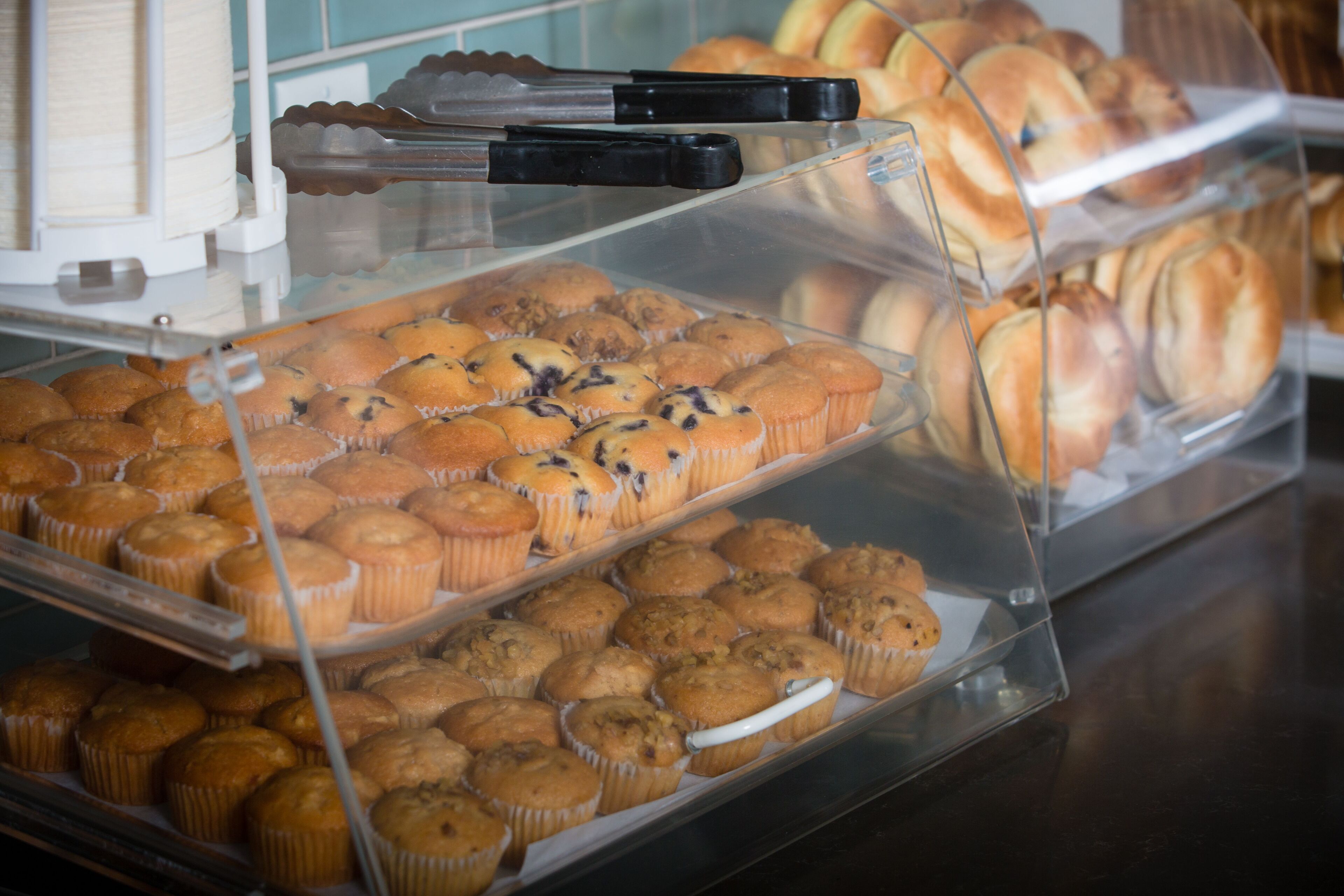 A bakery display case with various muffins and pastries.