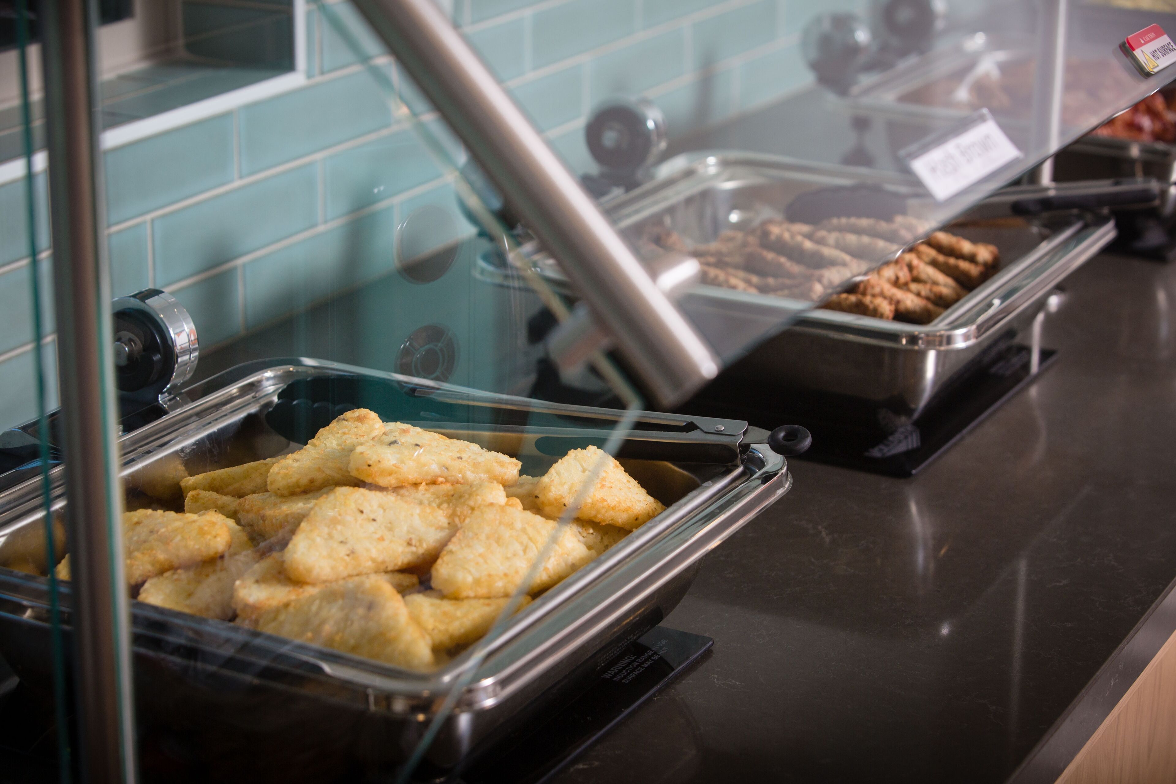 A buffet with various food items, including breaded items and pastries, displayed in clear containers.