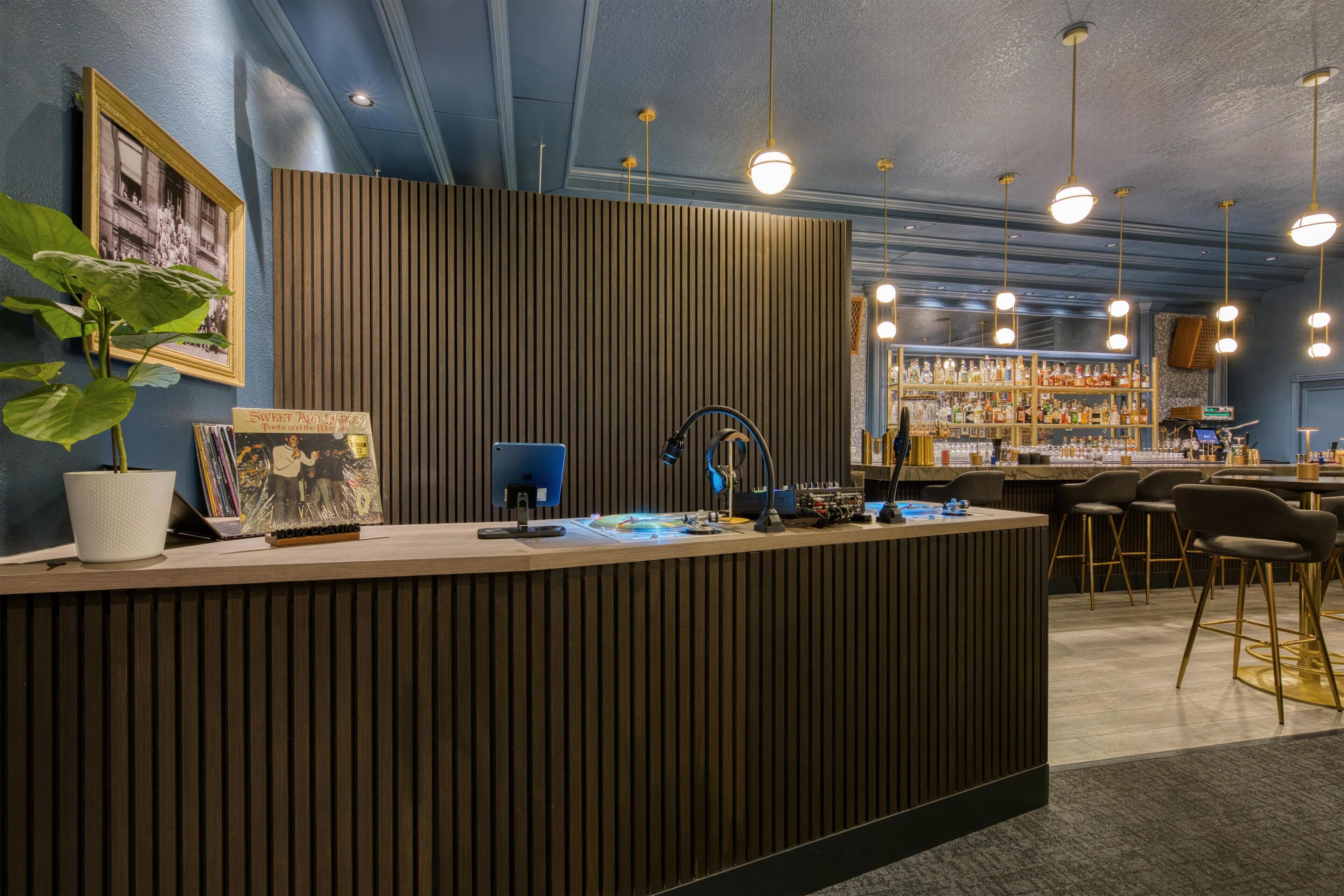 Una mesa de recepción con un panel de madera decorativo, una planta en maceta y una fotografía enmarcada.
