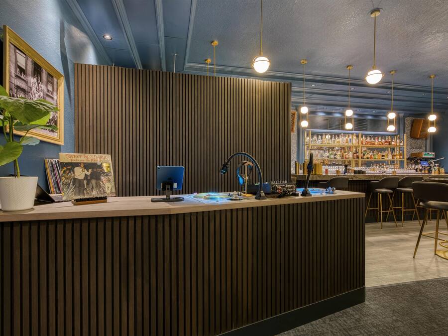 A reception desk with a wooden panel backdrop, a potted plant, and a framed photograph.