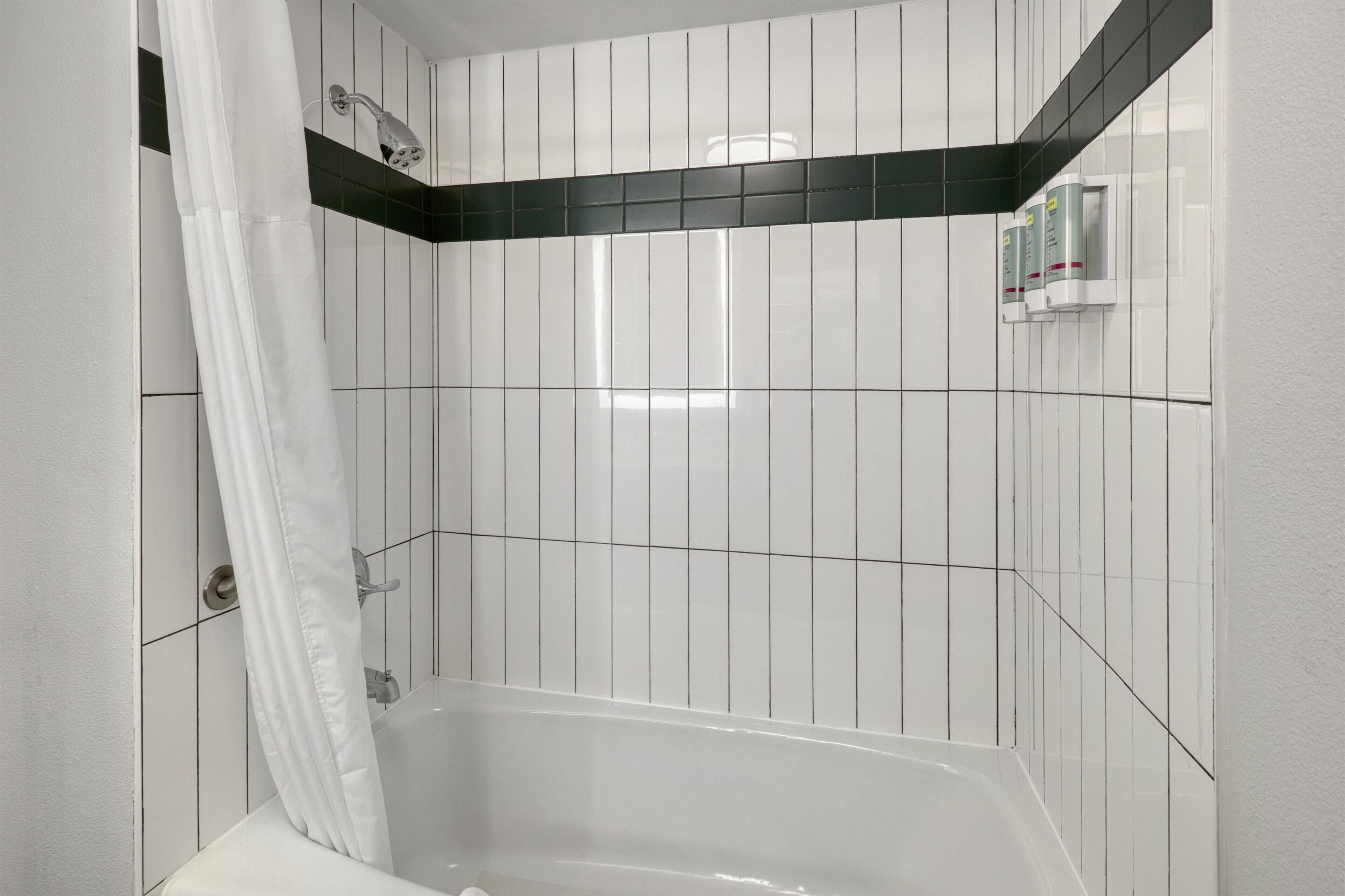 A modern bathroom with white and black tiles, a bathtub, and a shower curtain.