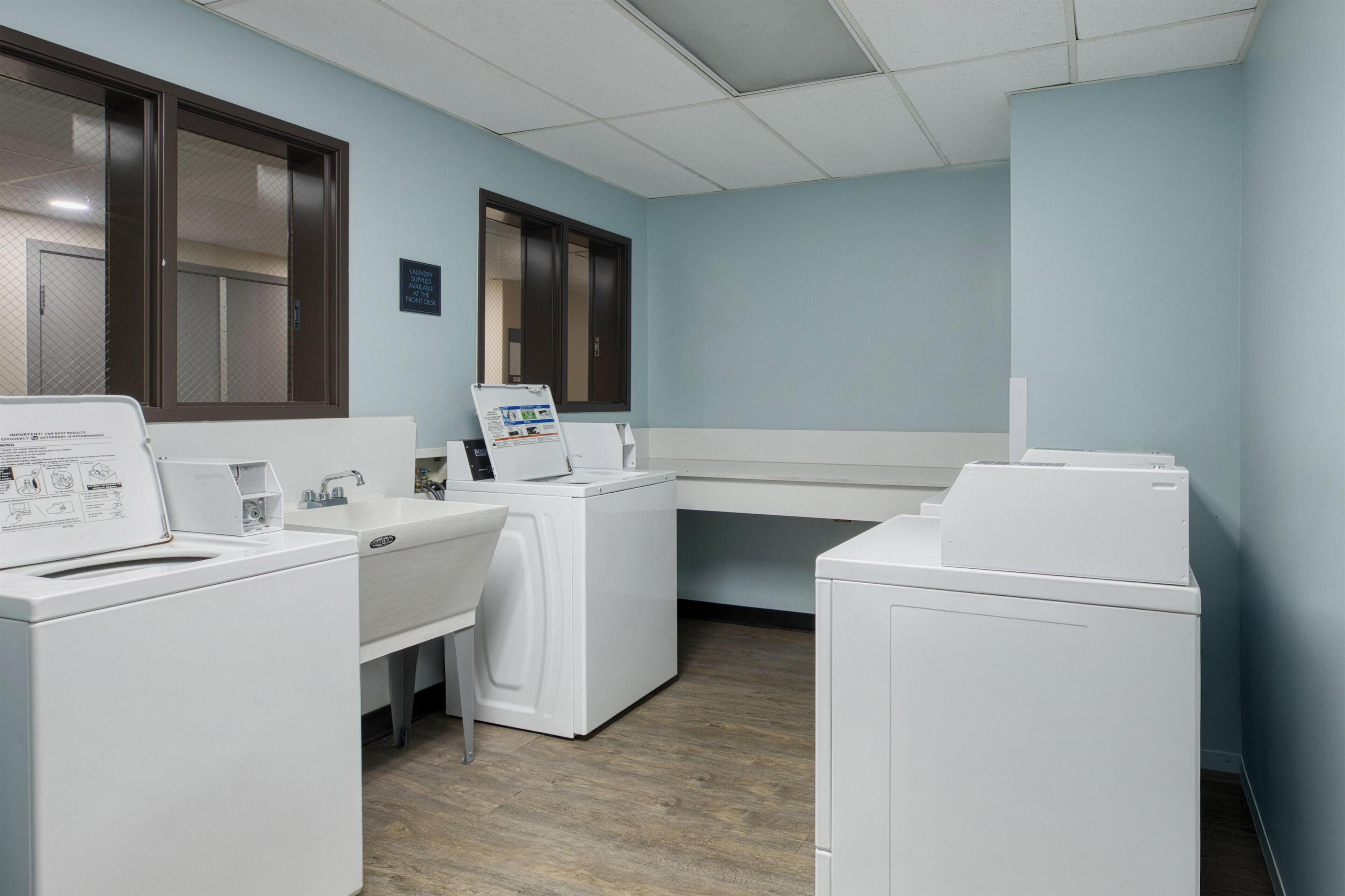 A laundry room with a washing machine, dryer, and a folding station.