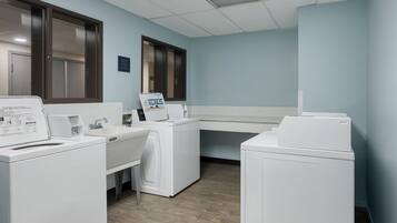 A laundry room with a washing machine, dryer, and a folding station.
