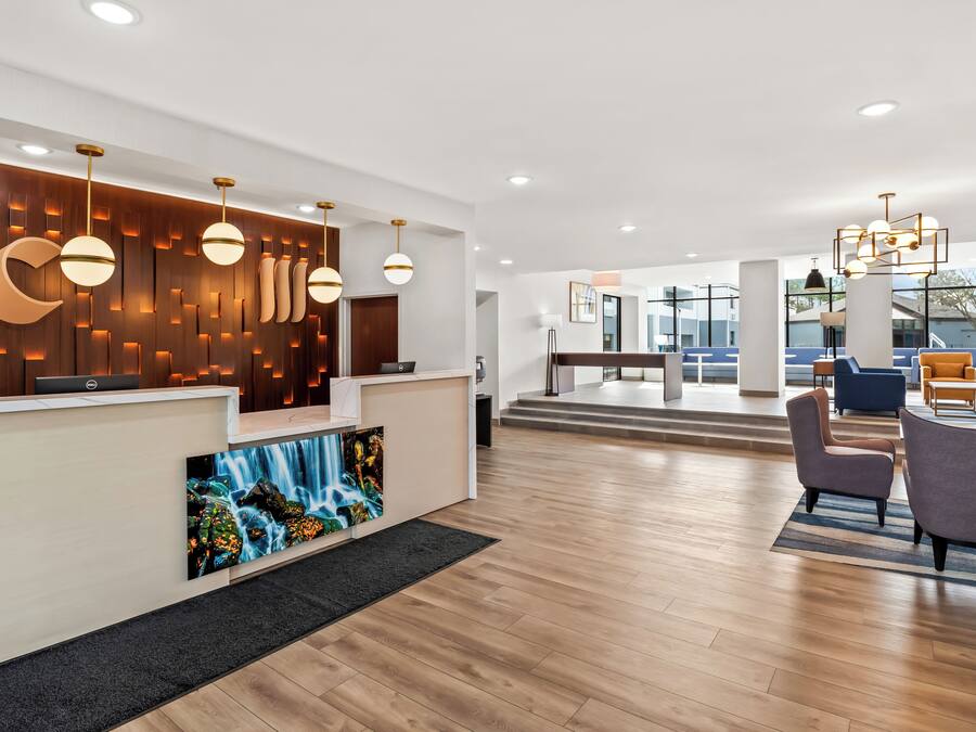 Un espace d’accueil moderne avec un mur en bois, un grand écran numérique et des luminaires au design contemporain.