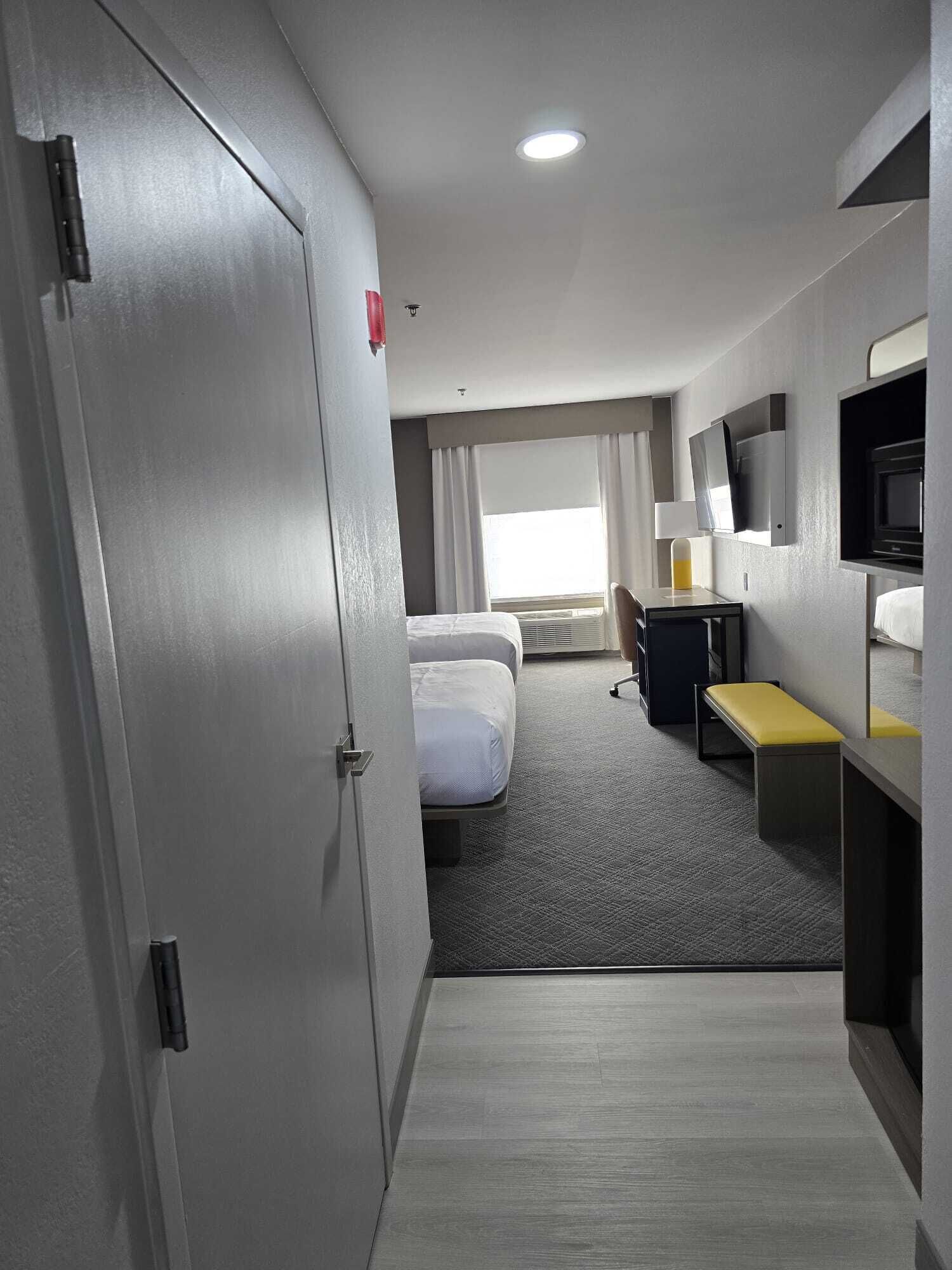 A hotel room with a bed, a desk, a chair, a TV, and a window.