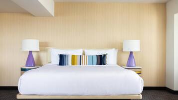 A hotel room with a large bed, two bedside lamps, and a wooden headboard.