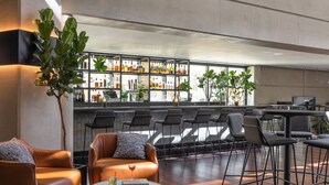 A modern bar area with leather chairs, a round table, and a bar stocked with various bottles.