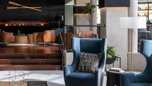 A modern lobby with a central staircase, seating areas, and a bar with a visible fireplace.