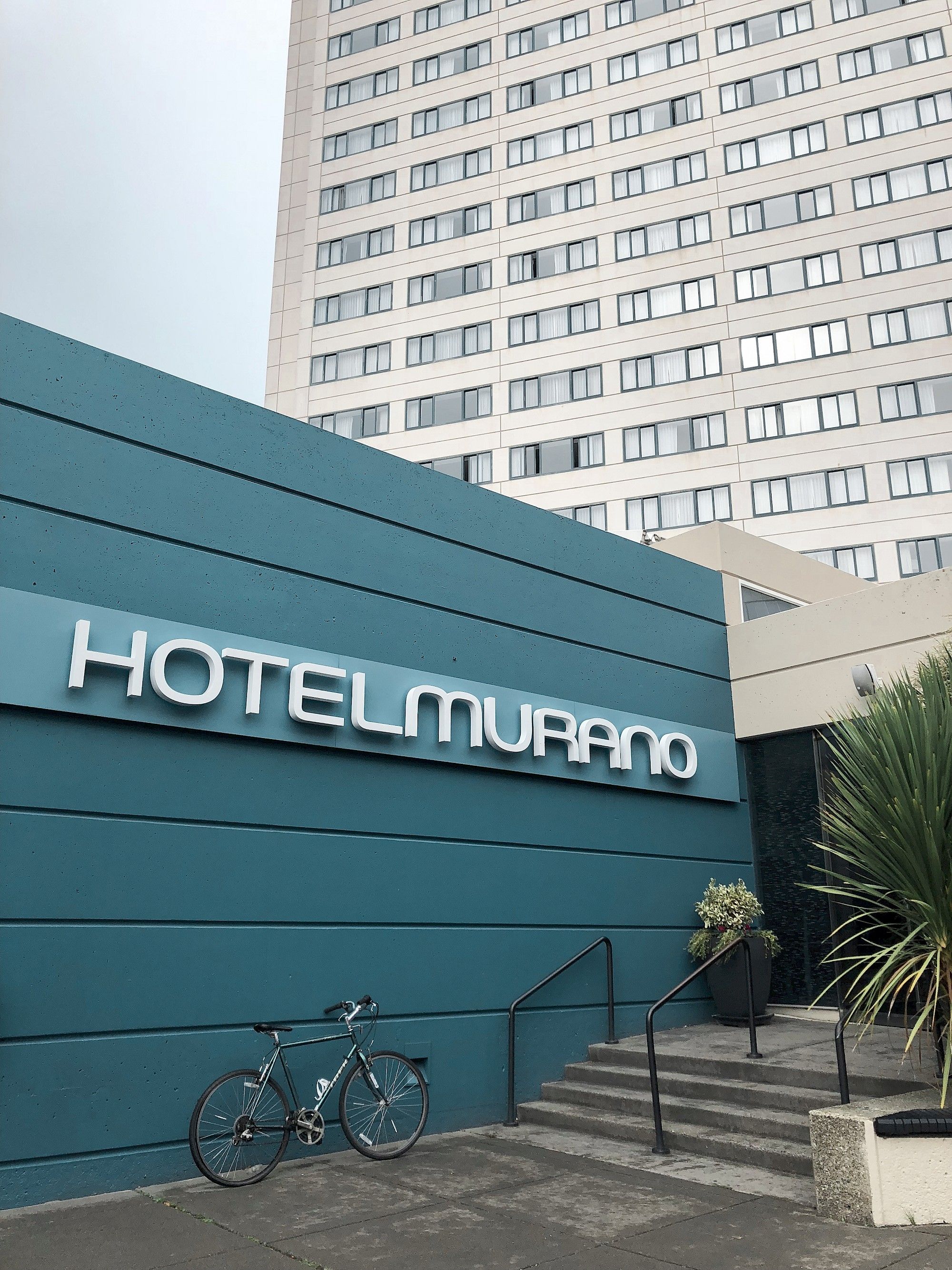 Ein Hotel Eingang mit einem Schild, auf dem 'HOTELMURANO' steht, und ein Fahrrad davor geparkt.